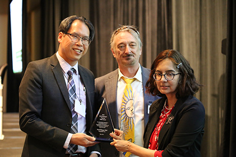 Paul Wang stands with his award trophy alongside Eric Miller and Sunita Satyapal.