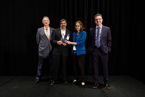 Four people stand with an award trophy.