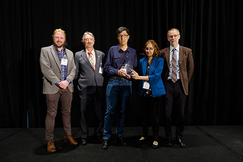 Five people stand with an award trophy.